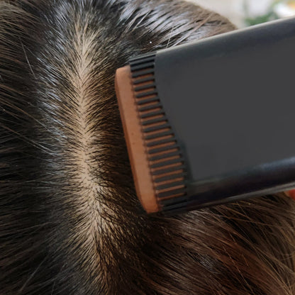 Person using a hairbrush on their head with a blurred background